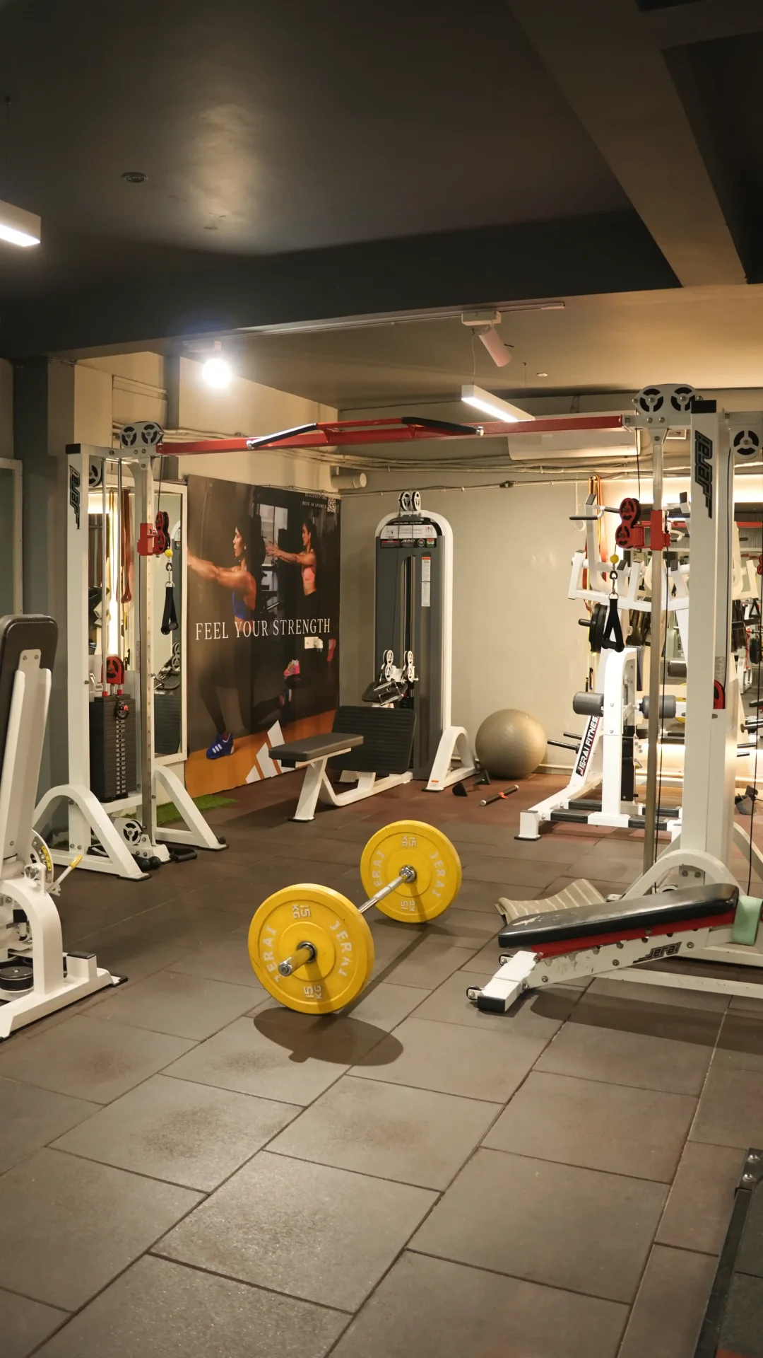 Strength zone with loaded barbell, cable machines, and motivational banner